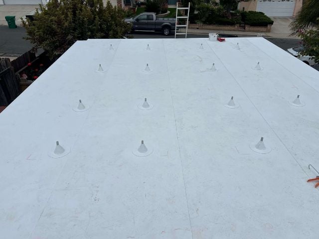  A person performing work on a white roof in the San Diego region 