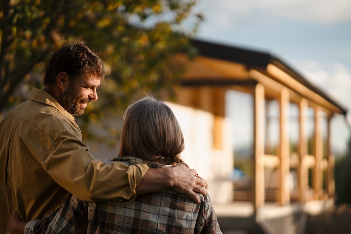 Mature couple looking at their new house under construction, planning future and dreaming. A mature couple looking at their new house under construction