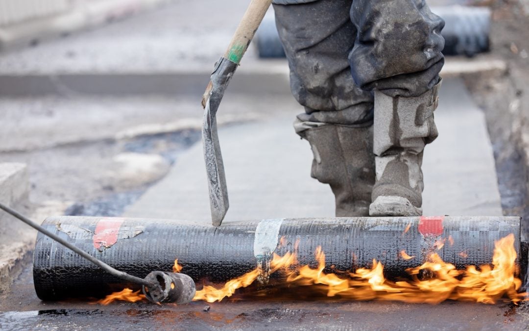 blow torch heating roll of roofing material