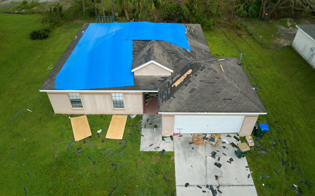 Top view of leaking house roof covered with protective tarp sheets against rain water leaks until replacement of asphalt shingles. Damage of building rooftop as aftermath of storm