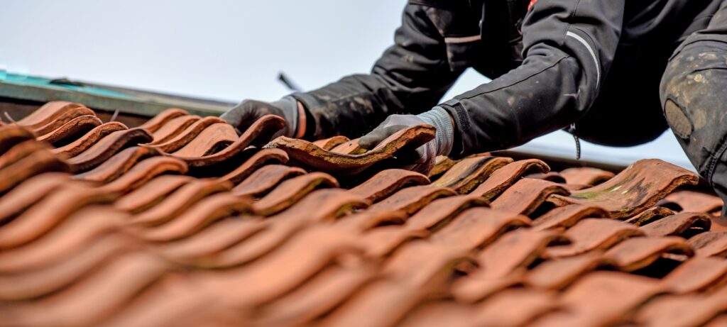 Worker adding Red tiles to roof