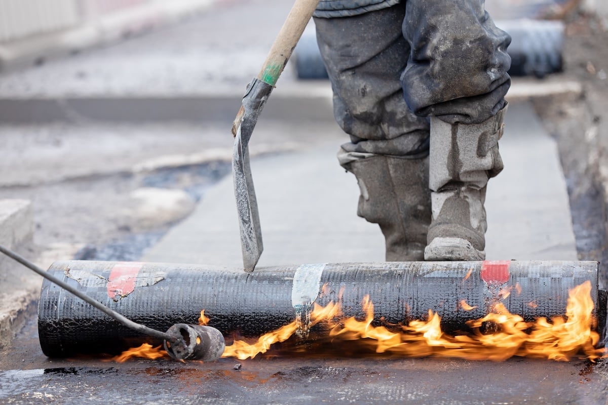 blow torch heating roll of roofing material