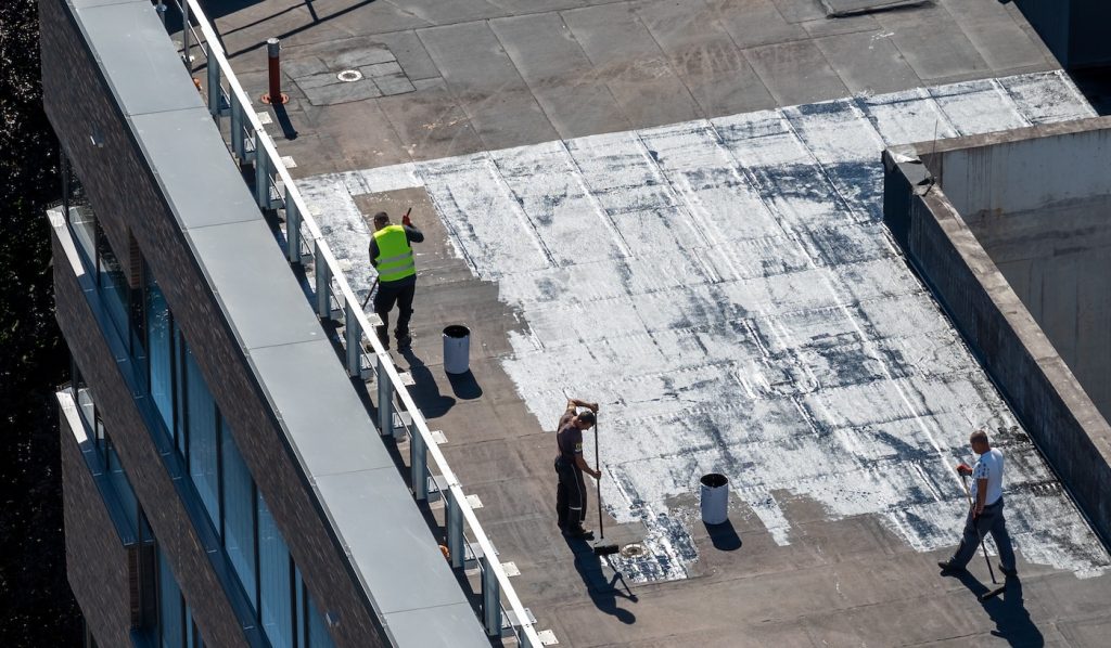 Birds eye view of a roof construction site. Professional bitumen waterproofing on a flat building.