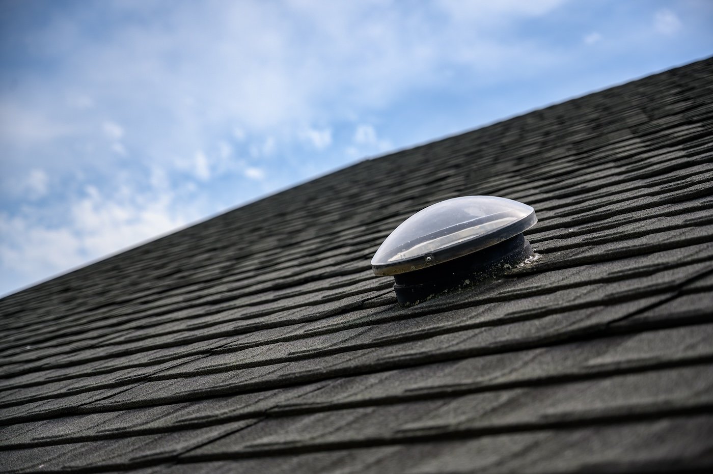 Dome shaped solar tube skylight on asphalt shingle roof