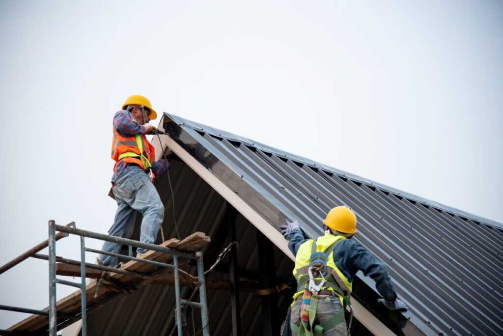 commercial roofers two workers on roof installing metallic