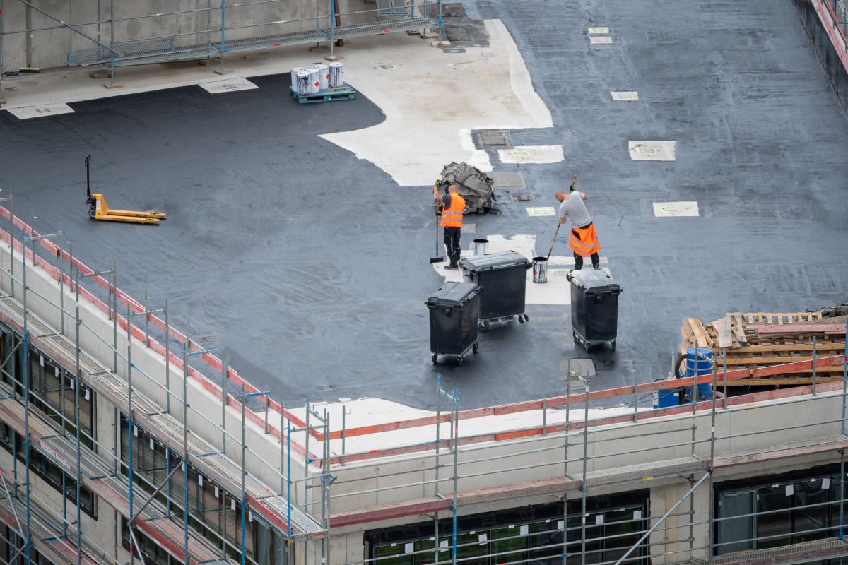 commercial roofers workers applying black cover