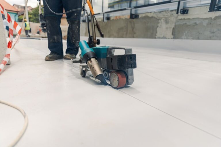 tpo roofing installation worker using heating tool with roller