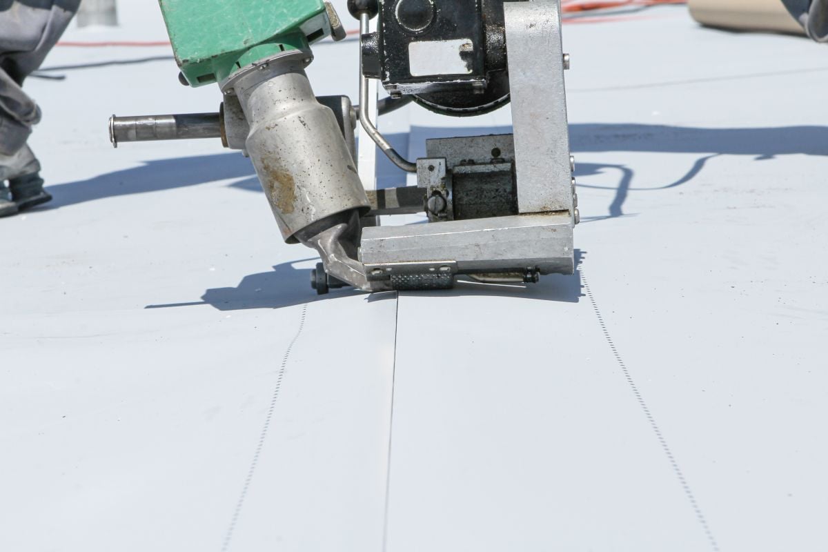 pvc roofing sheets worker applying white membrane on flat roof