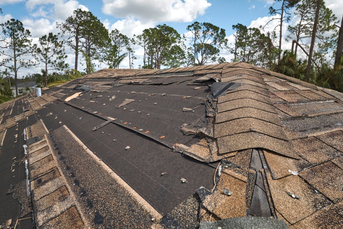 sagging roof Wind damaged house roof with missing asphalt shingles after hurricane Ian in Florida. Repair of home rooftop concept.