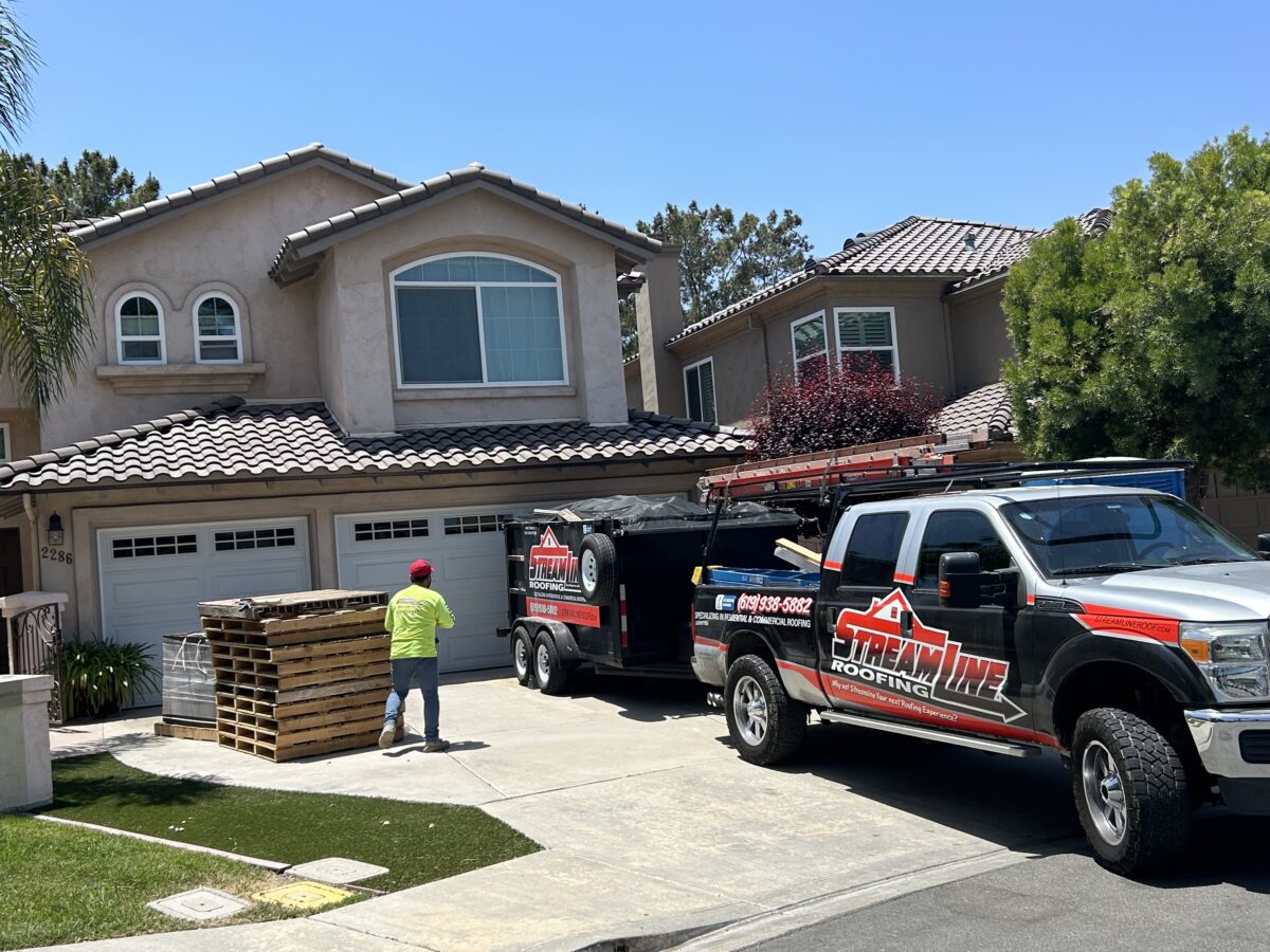 missing shingles worker outside house next branded truck parked