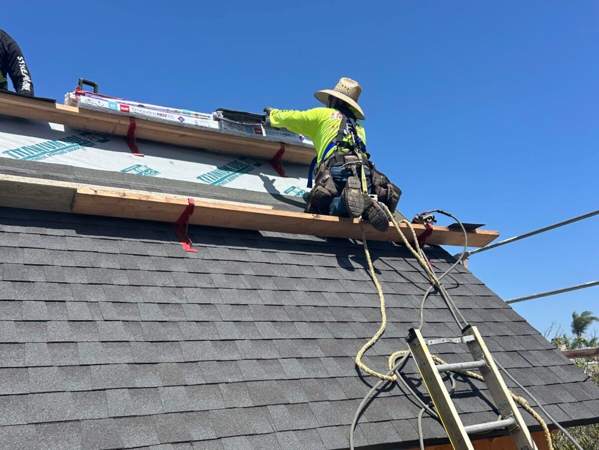 sagging roof worker on top of shingles roof