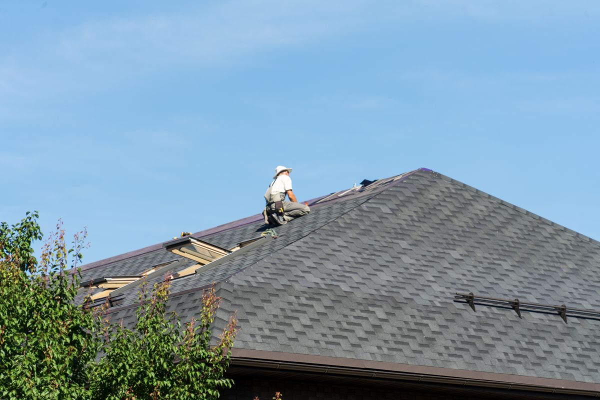 roof replacement cost aerial view of worker replacing shingles